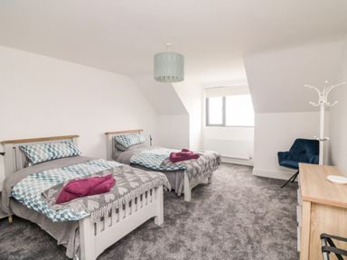 A bedroom with two single beds a wooden dresser a blue chair and a window at Old Field House in Slade near Fethard-On-Sea County Wexford