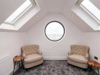 A small sitting area with two beige armchairs a round window and two skylights at Old Field House Slade near Fethard-On-Sea County Wexford