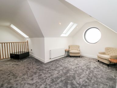 A room with two beige armchairs a small wooden table a black coffee table and circular window at Old Field House in Slade near Fethard-On-Sea County Wexford