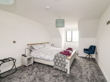 A bedroom with a double bed bedside table a blue chair and a window at Old Field House in Slade near Fethard-On-Sea County Wexford