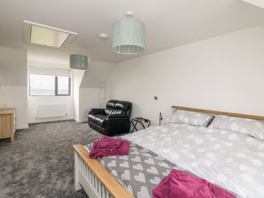 A bedroom with a bed a black leather armchair a window and a dresser at Old Field House Slade near Fethard-On-Sea County Wexford