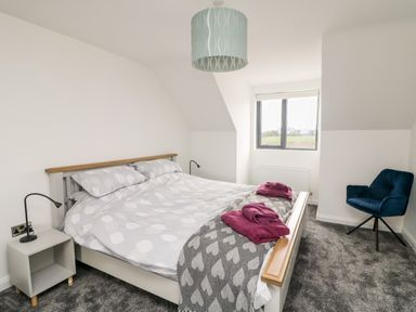 A bedroom with a bed side table and a blue chair at Old Field House Slade near Fethard-On-Sea County Wexford