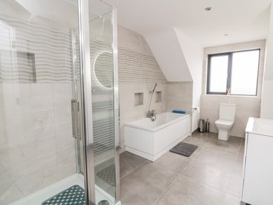 A bathroom with a shower, bathtub, toilet, and sink at Old Field House Slade near Fethard-On-Sea County Wexford