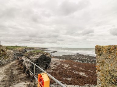A coastal path with rocky cliffs and seaweed along the shore at Old Field House Slade near Fethard-On-Sea County Wexford