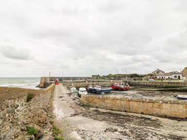 A small harbor with boats docked by stone walls and buildings near the sea at Old Field House in Slade near Fethard-On-Sea County Wexford