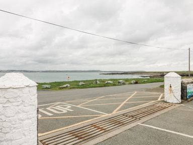 A paved road with stop lines and cattle grid with white stone pillars on each side by the coast at Old Field House Slade near Fethard-On-Sea County Wexford