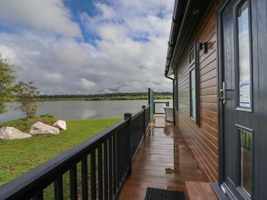 A wooden deck with black railing and a lake view at 40 Delamere Point in Delamere