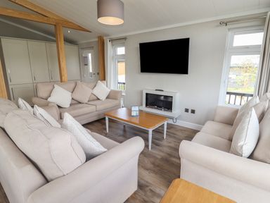 A living room with two beige sofas a wooden coffee table and a wall mounted television at 40 Delamere Point in Delamere