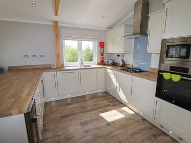 A kitchen with wooden countertops white cabinets a gas stove oven microwave toaster kettle and a window at 40 Delamere Point in Delamere