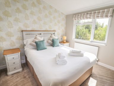 A bedroom with a double bed two bedside tables and a window at 40 Delamere Point in Delamere