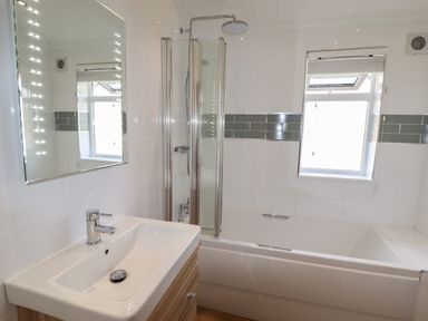 A bathroom with a sink, mirror with lights, bathtub, showerhead, and window at 40 Delamere Point in Delamere