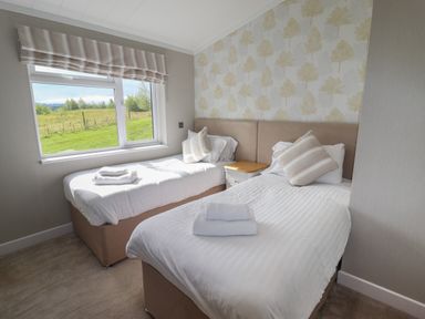 A bedroom with two single beds and a window showing a grassy field at 40 Delamere Point in Delamere