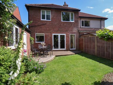 A backyard garden with a patio table and chairs outside a two-story brick house at North Bay Cottage in Bridlington