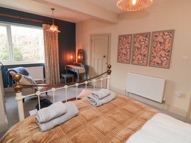 A bedroom with a bed folded towels a chair a dressing table with a mirror and three framed pictures on the wall at North Bay Cottage in Bridlington