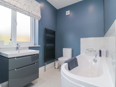 A bathroom with a bathtub a toilet a sink with a cabinet and a window at North Bay Cottage in Bridlington