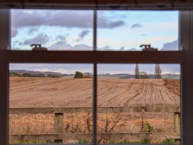 A view of fields and a wooden fence through a window at Robins Nest in Pocklington