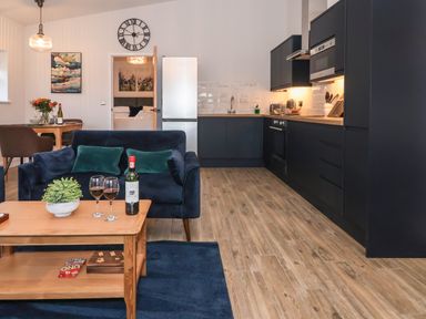 A kitchen and living area with blue sofa and wooden coffee table at Robins Nest in Pocklington