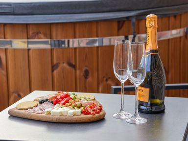A table with a bottle of prosecco two empty champagne glasses and a wooden board with assorted meats cheese olives and crackers at Robins Nest in Pocklington