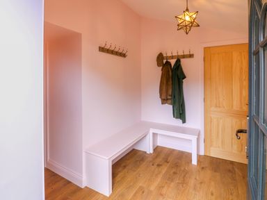 An entryway with wooden floor a wooden door white bench coat hooks with coats and a star-shaped light at The Coach House Great Whittington near Corbridge