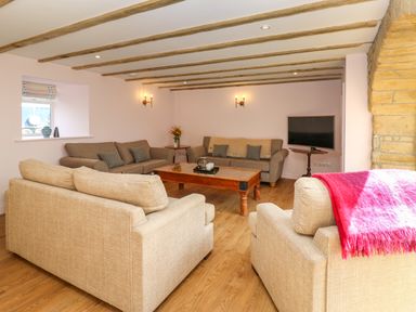 A living room with beige sofas a wooden coffee table a television and wooden ceiling beams at The Coach House in Great Whittington near Corbridge
