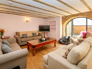 A living room with sofas coffee table television and a dog on a beanbag at The Coach House in Great Whittington near Corbridge