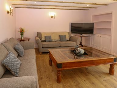 A sitting room with two sofas a wooden coffee table a television and a flower vase at The Coach House Great Whittington near Corbridge