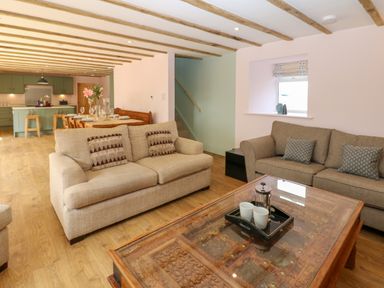 A living room with two sofas a wooden coffee table and an open kitchen with dining area at The Coach House in Great Whittington near Corbridge