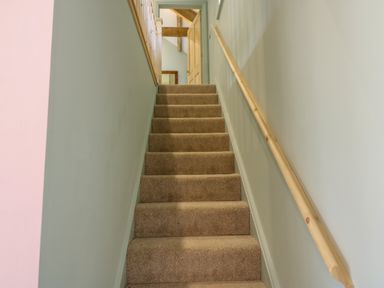 A carpeted staircase with a wooden handrail and an open door at the top at The Coach House in Great Whittington near Corbridge