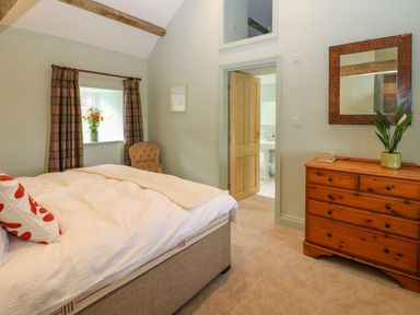 A bedroom with bed chest of drawers and open door to bathroom at The Coach House Great Whittington near Corbridge