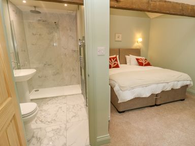 A bedroom with a double bed and an en suite bathroom with a shower at The Coach House in Great Whittington near Corbridge