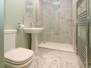 A bathroom with a toilet sink shower area and a towel radiator at The Coach House in Great Whittington near Corbridge