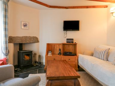 A living room with a wood stove and wooden furniture at Aunt Dora's in Port Isaac