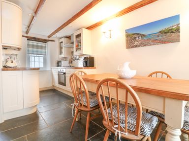 A kitchen with wooden dining table and chairs and kitchen cabinets at Aunt Dora's in Port Isaac
