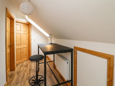 A small room with a black table and stool under a sloped ceiling near wooden doors at Old Field Hideaway Slade near Fethard-On-Sea County Wexford
