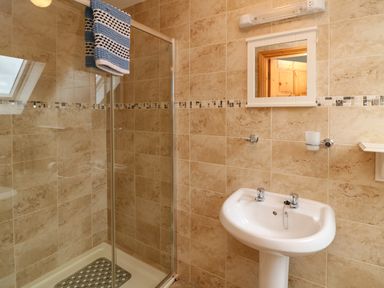 A bathroom with a glass shower enclosure and a white pedestal sink at Old Field Hideaway Slade near Fethard-On-Sea County Wexford