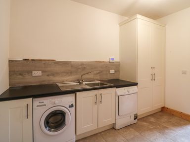 A utility room with washing machine dryer sink cabinets and tiled floor at Old Field Hideaway Slade near Fethard-On-Sea County Wexford