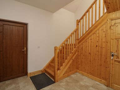 A hallway with wooden stairs wooden doors and tiled floor at Old Field Hideaway Slade near Fethard-On-Sea County Wexford