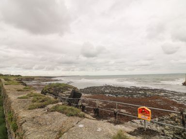A rocky coastline with a stone wall and a lifebuoy on a railing at Old Field Hideaway Slade near Fethard-On-Sea County Wexford