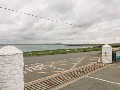 A road with a stop sign and cattle grid near a grassy area by the sea at Old Field Hideaway Slade near Fethard-On-Sea County Wexford