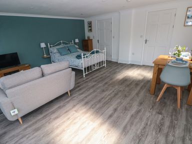 A studio room with a bed sofa television and dining table at Tower Cottage Near Pembroke