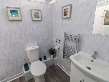 A bathroom with a toilet sink towel rack and framed pictures on the wall at Tower Cottage Near Pembroke