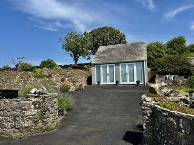 A house with flower pots and stone walls near a pathway at Tower Cottage Near Pembroke