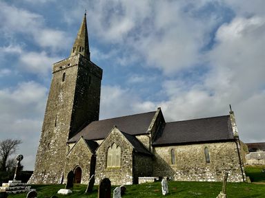 A church with a tower and gravestones near Pembroke at Tower Cottage