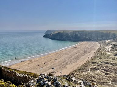 A beach with people walking near the water at Tower Cottage Near Pembroke