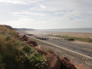 A view of a beach with cliffs grass rocks and wooden barriers at 8 Corkickle in Whitehaven