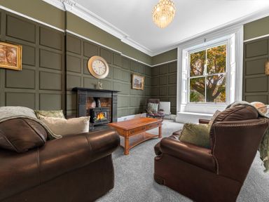 A living room with leather sofas a wooden coffee table fireplace and a large window at 8 Corkickle Whitehaven