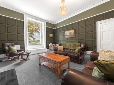 A living room with leather sofas a wooden coffee table and a window with a view at 8 Corkickle in Whitehaven