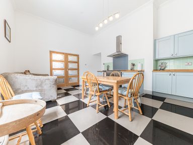 A kitchen with wooden dining table and chairs a sofa and light blue cabinets at 8 Corkickle in Whitehaven
