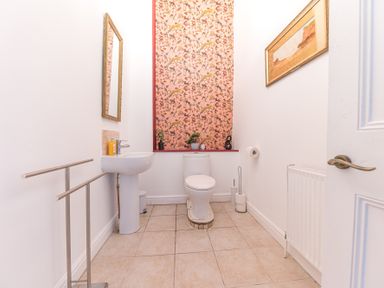 A bathroom with a toilet a pedestal sink a mirror towel rack and framed artwork at 8 Corkickle in Whitehaven