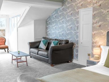 A bedroom with a leather sofa a wooden coffee table and a bedside table with a lamp at 8 Corkickle in Whitehaven